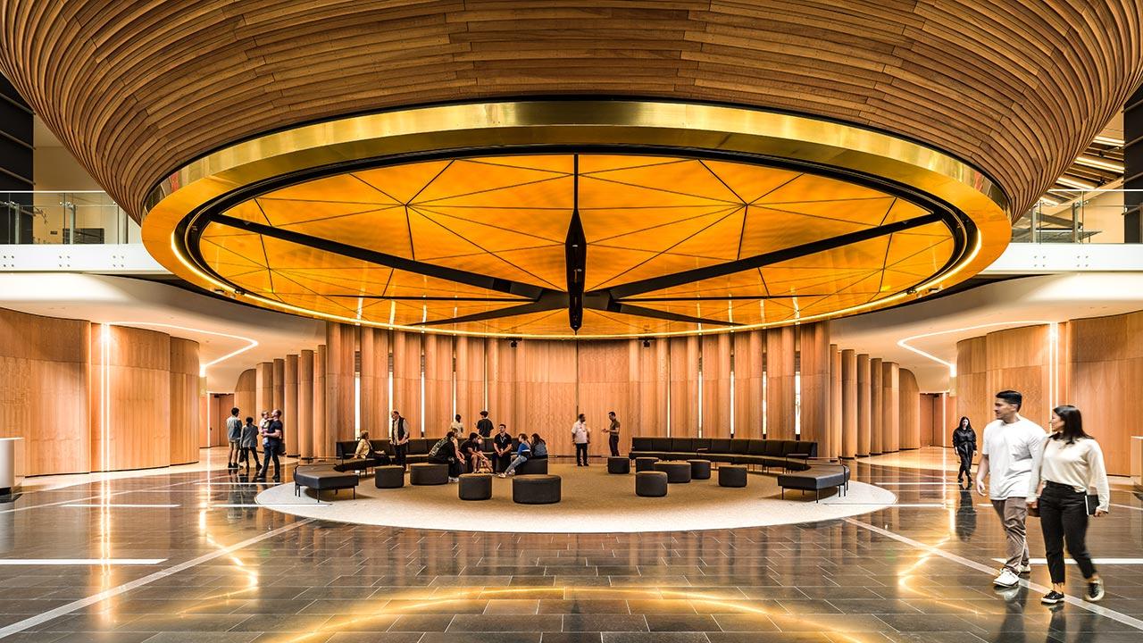 A museum lobby with a large architectural ceiling lighting sculpture above a seating area